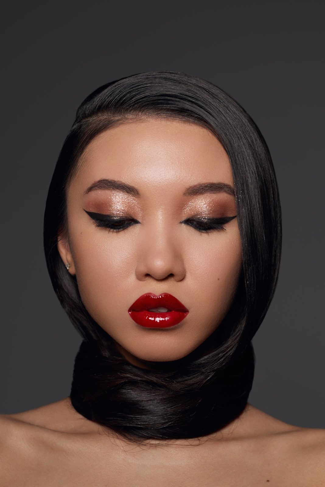 Bronze shimmer eyes, winged liner, glossy red lips, hair wrapped as a collar